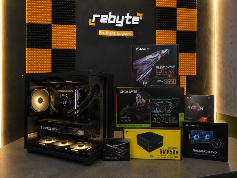 A completed Rebyte custom PC build with its component boxes — GPU, CPU, motherboard and PSU